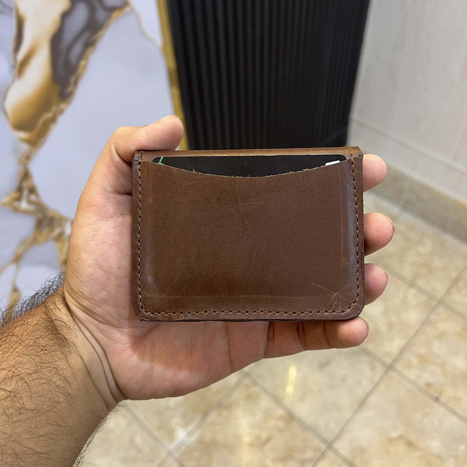 Hand holding a brown leather wallet against a blurred background