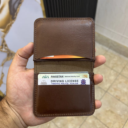 Brown leather wallet with a Pakistan driving license card inside, held by a hand.