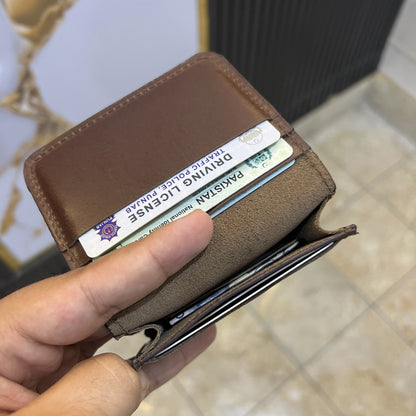 Brown wallet with a driver's license card held by a hand on a blurred background