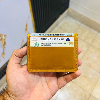 Hand holding a yellow card holder with a Pakistan driving license inside.